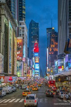 a city street filled with lots of traffic and tall buildings in the background at night