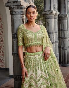 Editor's Note Ivory Tulle Lehenga Choli And Dupatta With A Contrasting Lime Embroidery In Gota, Resham, Crystals, Sequins, And Beads. Color: Ivory Lime Components: Lehenga, Blouse & Dupatta Fabric: Tulle Care: Dry Clean Only About the Designer Nitika Gujral’s journey with designing clothes started almost four decades back while she was still in high school and held her first exhibition for family and friends. Making clothes has been a part of her life ever since. Fitted Net Choli With Intricate Embroidery, Pista Green Embellished Organza Sets, Traditional Embellished Net Gown, Intricately Embroidered Fitted Net Sets, Intricate Embroidery Fitted Net Sets, Festive Cream Lace Sets, Lace Choli With Zari Work, Bollywood Style Lace Choli For Reception, Fitted Lace Choli With Zari Work