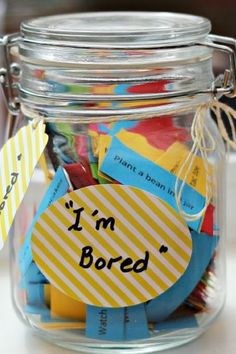 a glass jar filled with lots of different colored paper notes and tags that say i'm bored