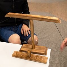 a woman sitting on the floor next to a desk with a wooden object in front of her