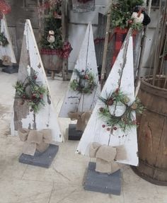 three wooden christmas trees with wreaths on them