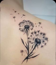 the back of a woman's shoulder with a dandelion tattoo