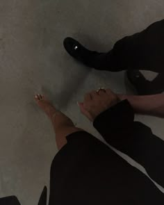 two people standing next to each other with their feet on the ground and one person wearing black shoes