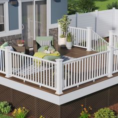 a deck with white railings and chairs on the side of it, in front of a house