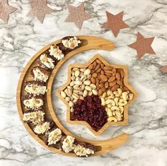 nuts, dried cranberries, almonds and raisins in a crescent on a marble surface