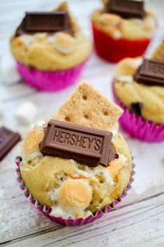 cupcakes with chocolate and marshmallow toppings are on a white table