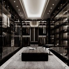 a large walk in closet with lots of clothes on the shelves and lights above it