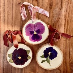 three pieces of wood with purple flowers painted on them and ribbon hanging from the top