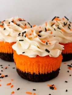 three cupcakes with white frosting and sprinkles on top are sitting on a plate