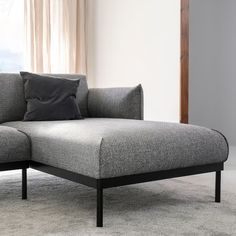 a gray couch sitting on top of a rug next to a window