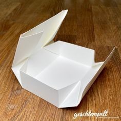 an origami box sitting on top of a wooden table with its lid open