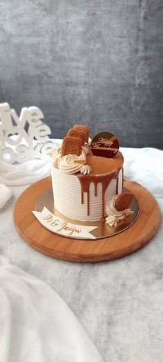 a cake with white frosting and chocolate icing on a wooden platter next to some cookies