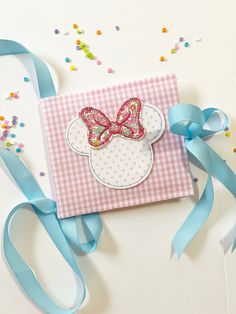 a card with a minnie mouse design on it and blue ribbon tied around the edge