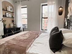 a bedroom with a bed, two windows and a desk in the back ground area