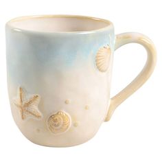 a ceramic mug with shells and starfishs on the inside, sitting in front of a white background