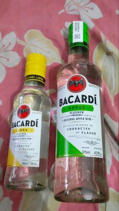 two bottles of bacardi water sitting on a bed