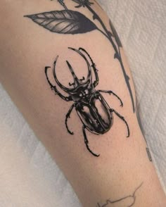 a black beetle sitting on top of a person's leg next to a flower