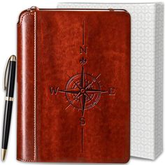 a notebook with a compass on the cover and a pen next to it, in front of a white background