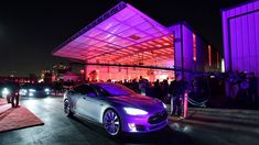 a car parked in front of a building with purple lights on it's side