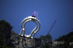 there is a man standing on top of a giant structure in the sky above some mountains