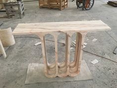 a wooden table sitting on top of a cement floor next to other woodworking supplies