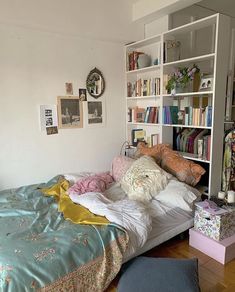 a bed sitting next to a book shelf filled with books