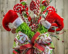 a christmas wreath with candy canes and santa hats on it, sitting in front of a wooden wall