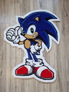 the sonic sticker is sitting on top of a wooden floor and has it's thumb up