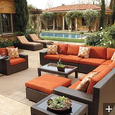 an outdoor living area with couches, tables and chairs in front of a swimming pool