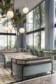 a restaurant with tables, chairs and plants in the window sill next to large windows