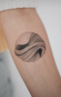 a woman's arm with a black and white wave tattoo on the left forearm