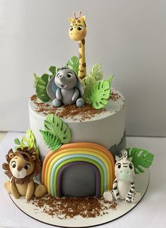 there is a cake decorated with animals and plants on the top one has a rainbow