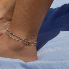 a woman's foot with a tattoo on it and a chain around the ankle