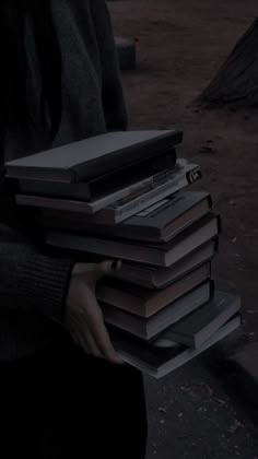 a person holding a stack of books in their hands