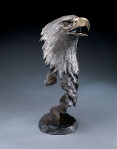 a statue of an eagle on a rock with its beak open and it's head in the air