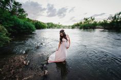 black and white photo of woman in flowing water with trees on the bank behind her