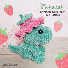 a crocheted stuffed animal with a pink flower on its head sitting in front of strawberries