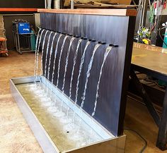 a large metal fountain with water running down it's sides in a workshop area