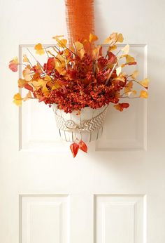 a potted plant hanging from the side of a door with fall foliage in it