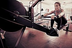 a woman squatting down on a bench in a gym with an exercise machine behind her