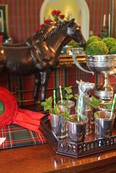 there is a tray with glasses and cups on it, next to a horse statue