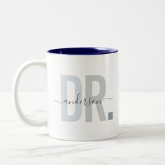 a white and blue coffee mug with the word dr in cursive writing on it