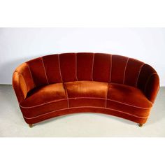 an orange curved couch sitting on top of a white floor