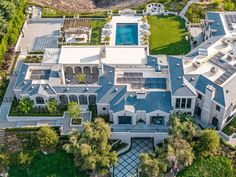 an aerial view of a large mansion surrounded by lush green trees and shrubs, with a swimming pool in the foreground