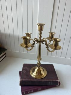 a brass candelabra on top of a book with three candles in it