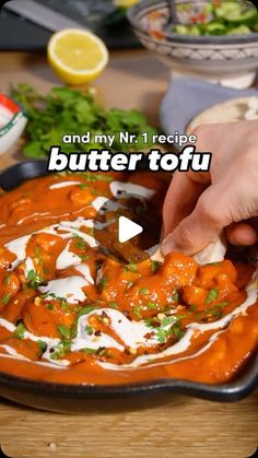 a person dipping sauce on top of food in a black bowl with the words butter tofu over it