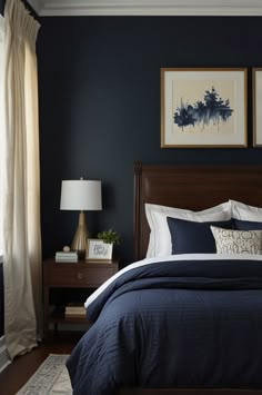 a bedroom with dark blue walls and white bedding, two framed pictures on the wall