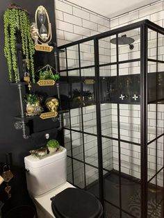 a white toilet sitting next to a black and white tiled shower stall in a bathroom