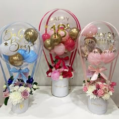 three vases filled with balloons and flowers on a table