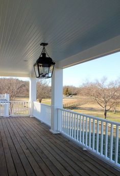 an empty porch with a lantern hanging from it's ceiling and wooden flooring